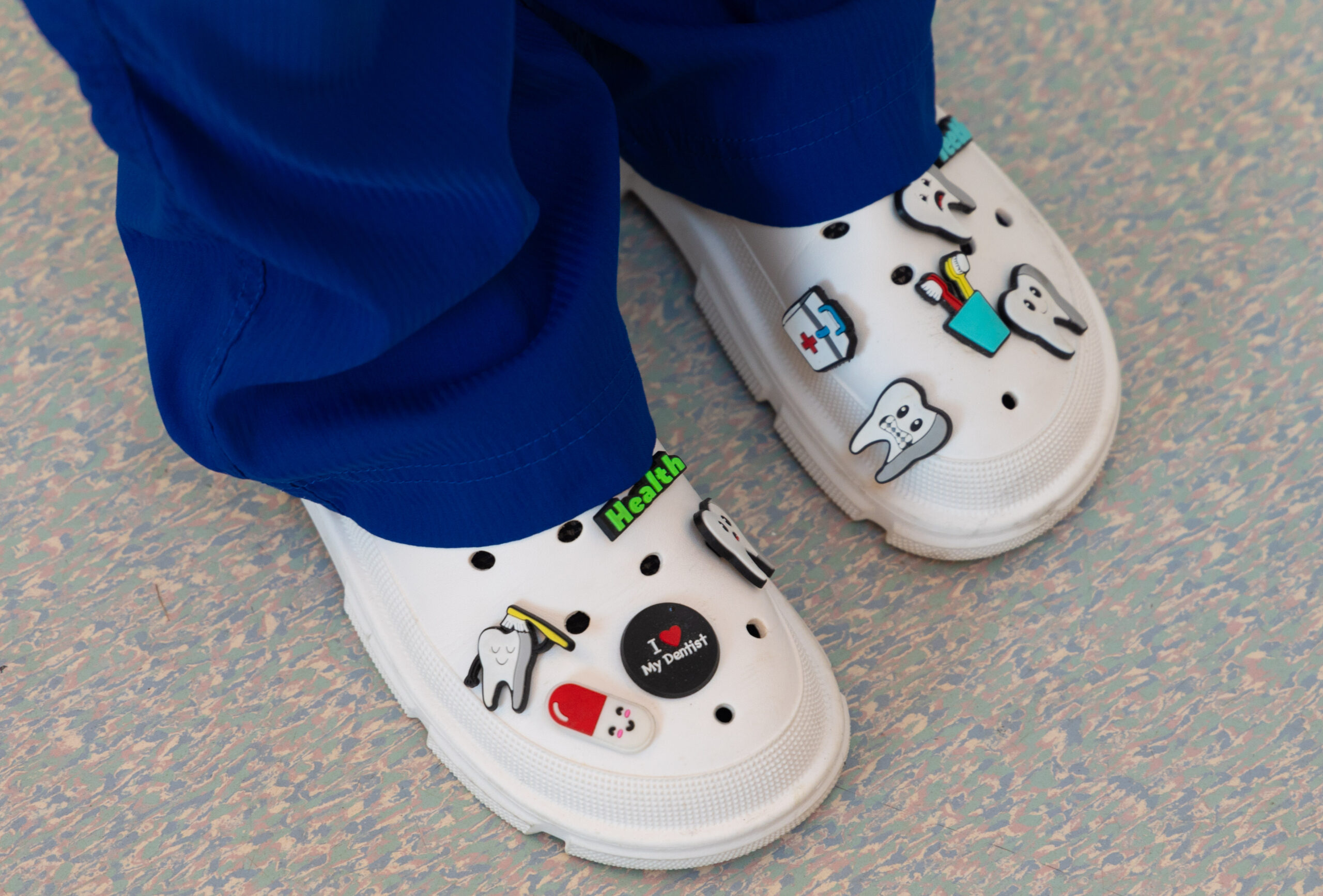 Dental nurse wearing white clinical clogs decorated with tooth and toothbrush charms