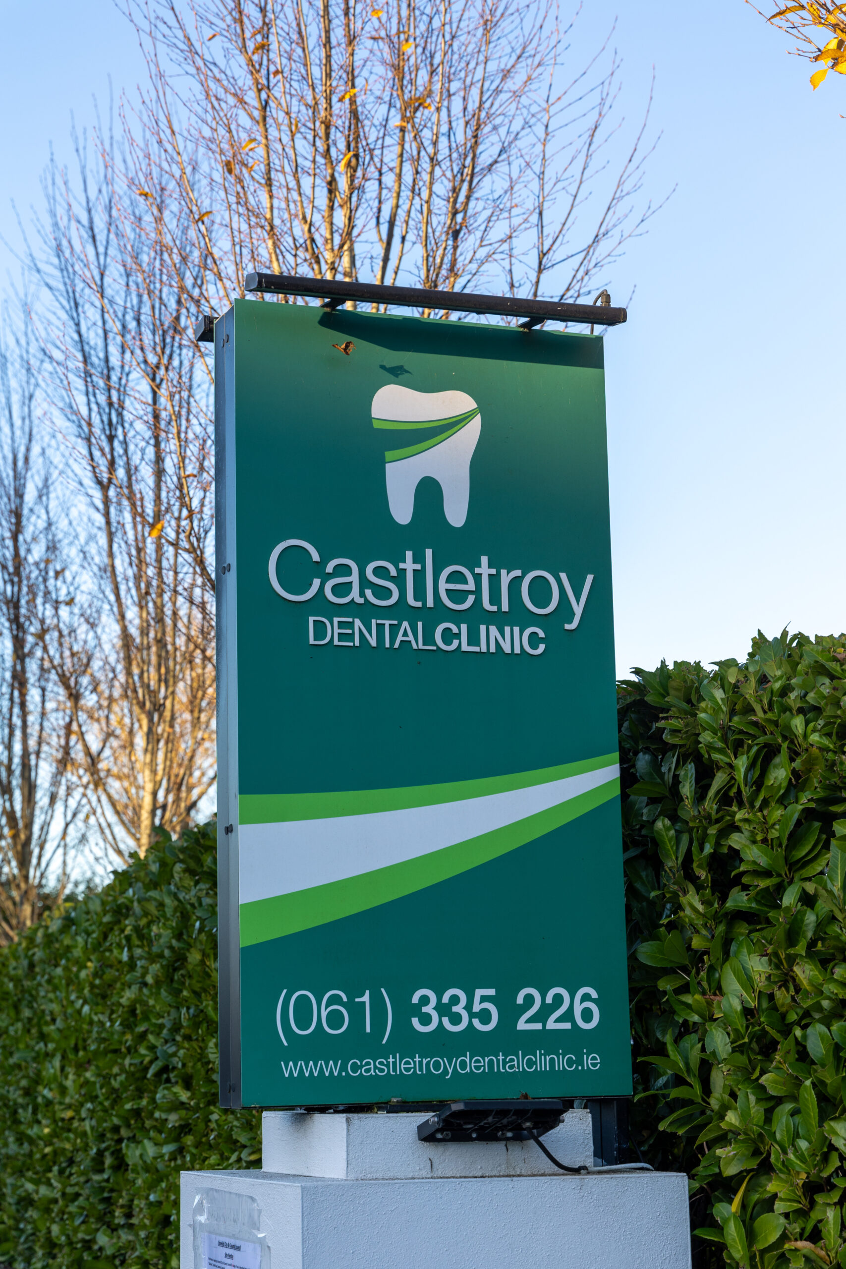 Green Castletroy Dental Clinic signpost showing the practice logo, website and phone number (061) 335 226
