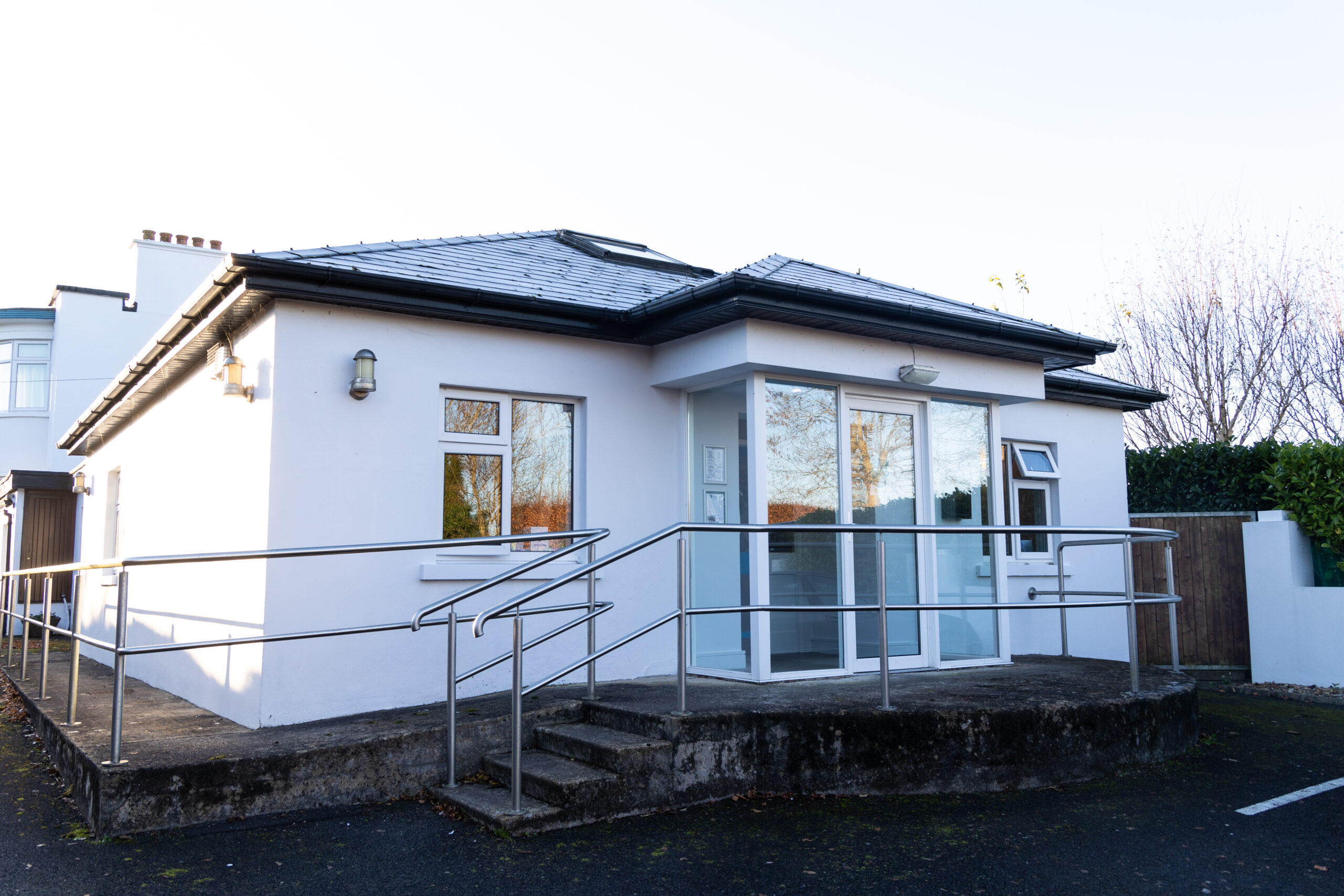 Step-free clinic entrance with a level access ramp and stainless steel handrails at Castletroy Dental Clinic