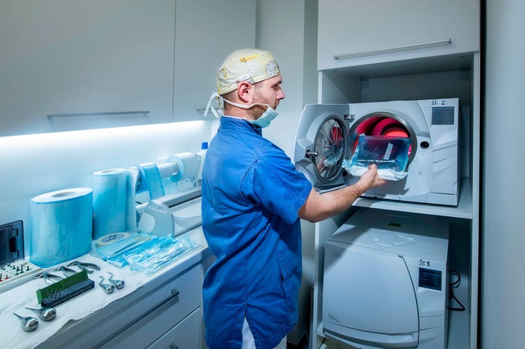 Dental nurse loading pouched instruments into a clinical autoclave steriliser